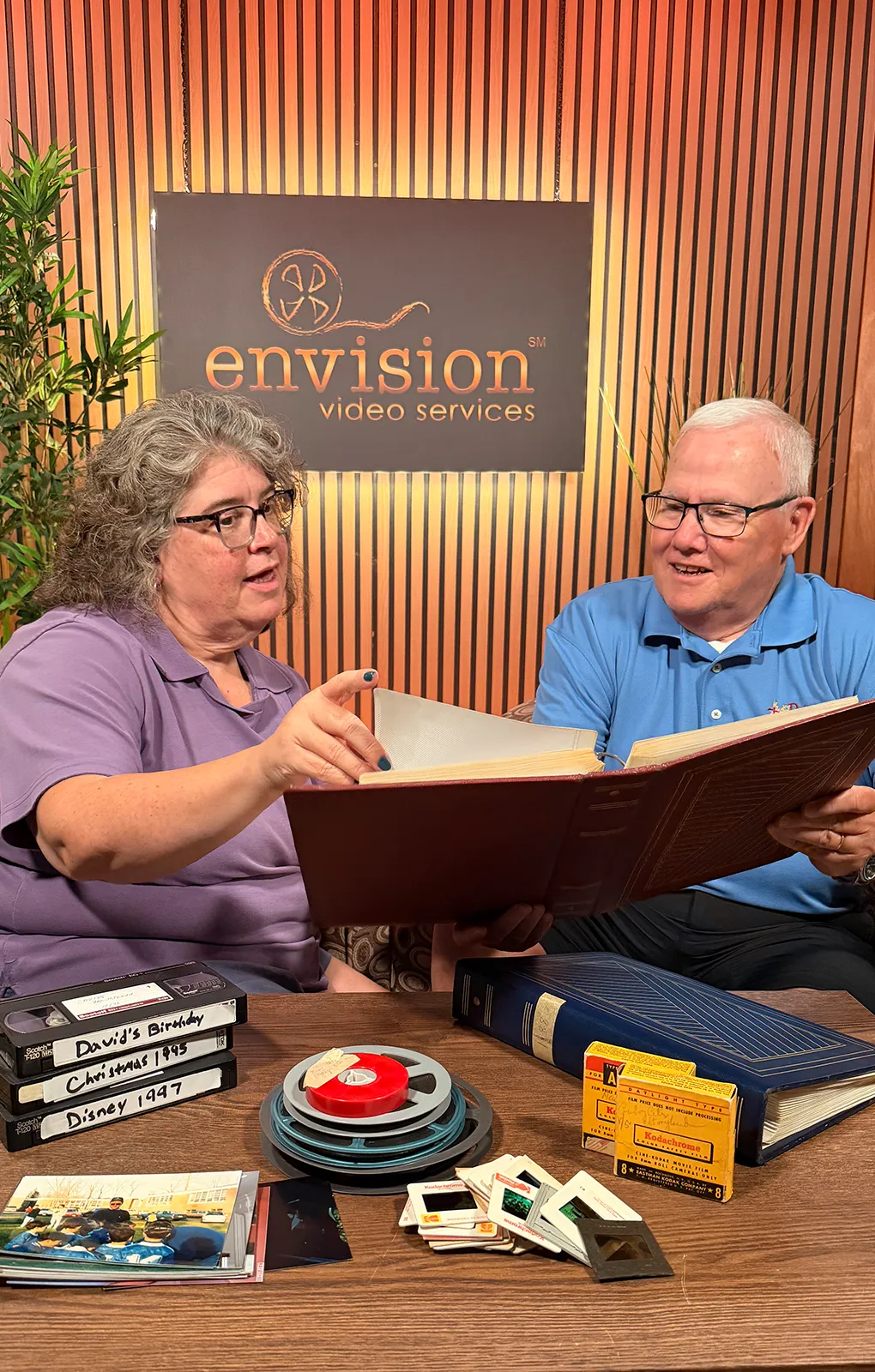 Customer reviewing a family photo album with Envision Video Services staff