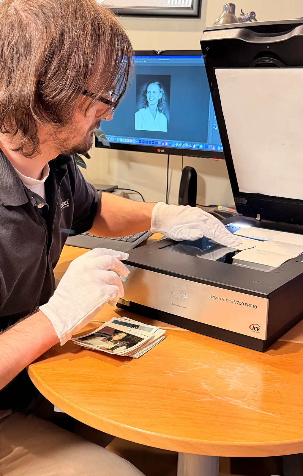 Envision Video Services technician scanning family photographs on a professional photo scanner