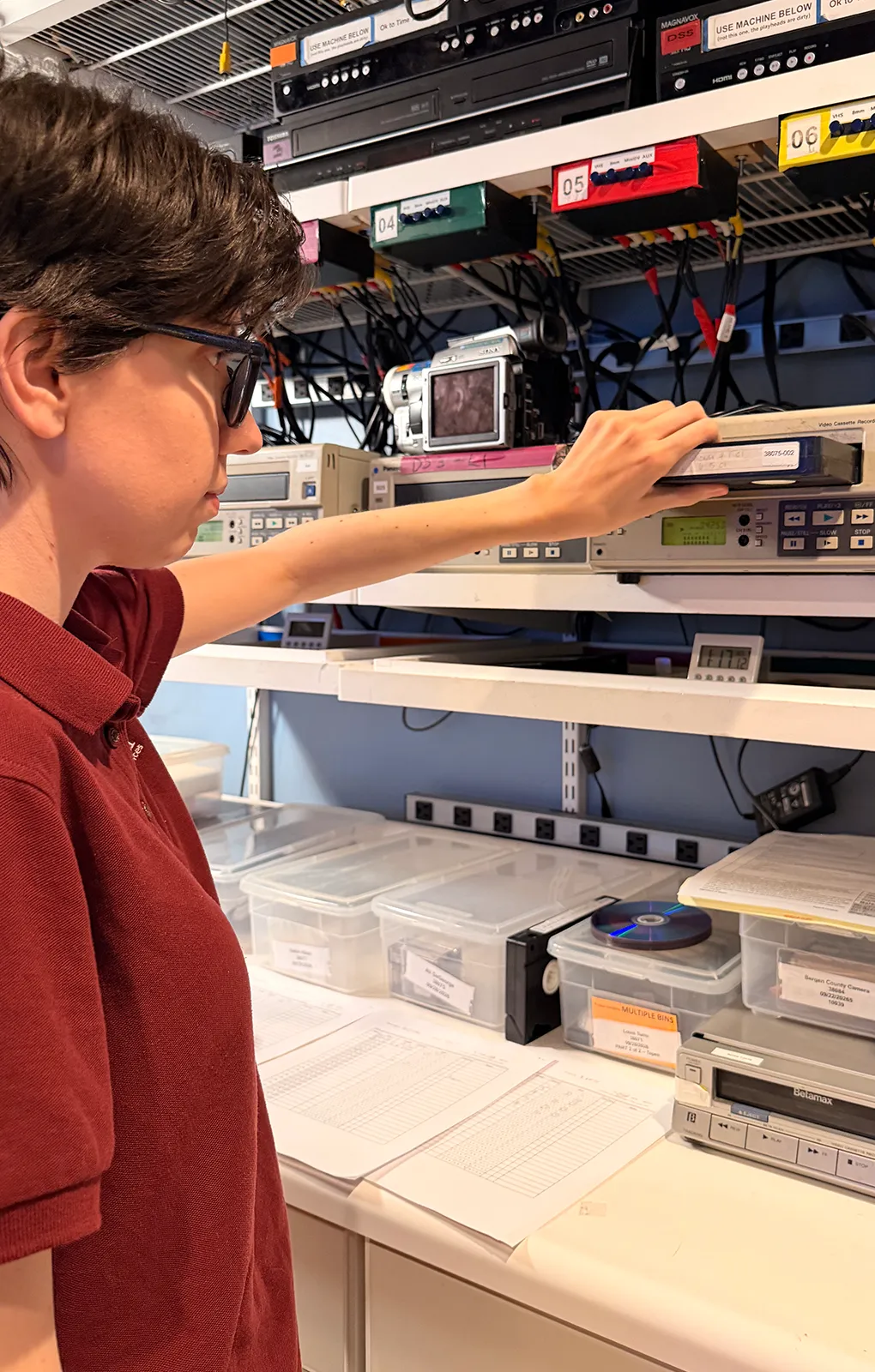 Envision Video Services technician inserting a VHS tape into professional video transfer equipment